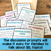 Educational discussion prompts on cards with text about SEL topics on a wooden surface.