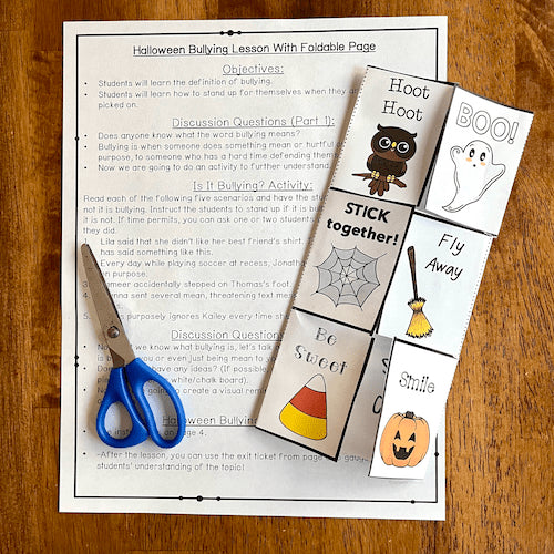 Halloween-themed bullying lesson with foldable pages and scissors on a wooden surface