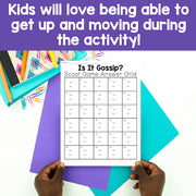 Sheet of paper with a grid titled 'Is It Gossip?' Scoot Game Answer Grid held by hands on a colorful background.