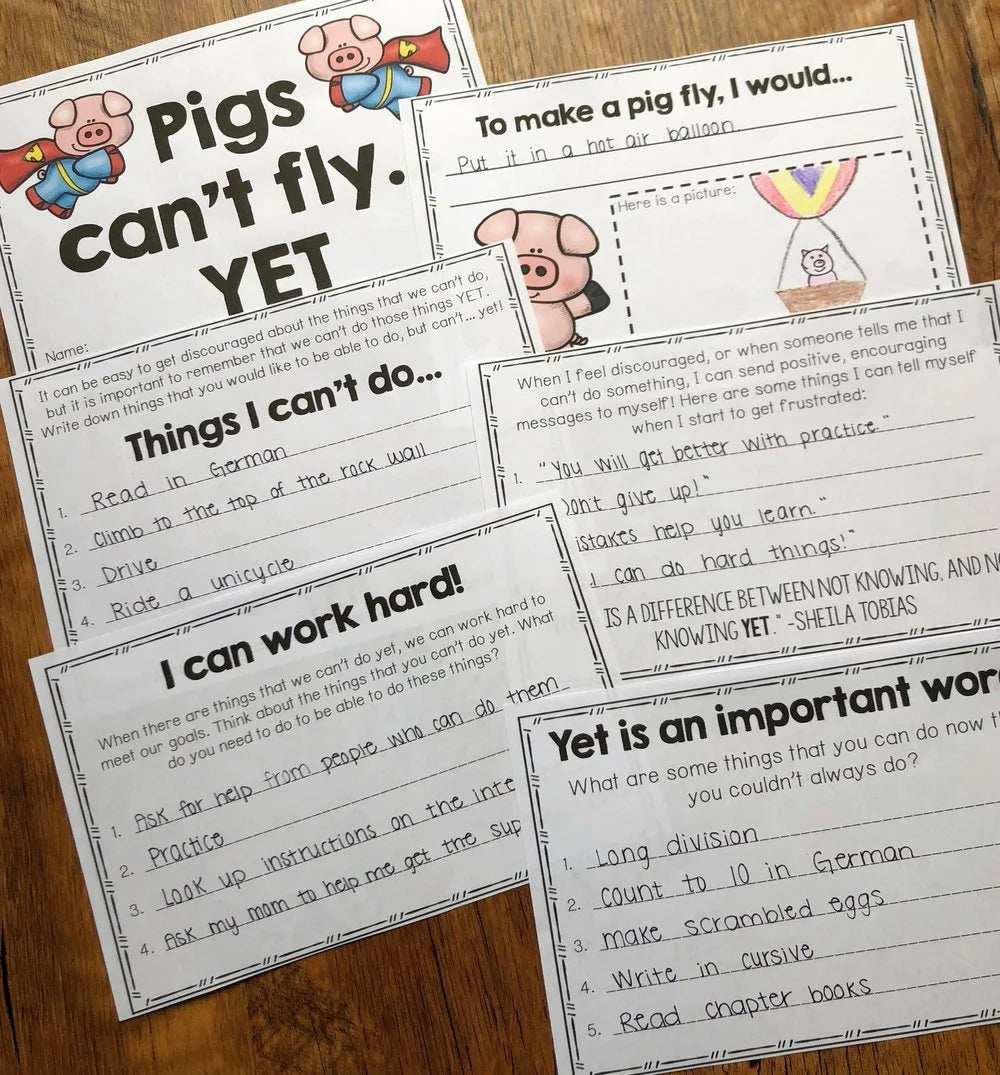 Educational worksheets on a wooden surface with text and graphics about self-confidence and hard work.